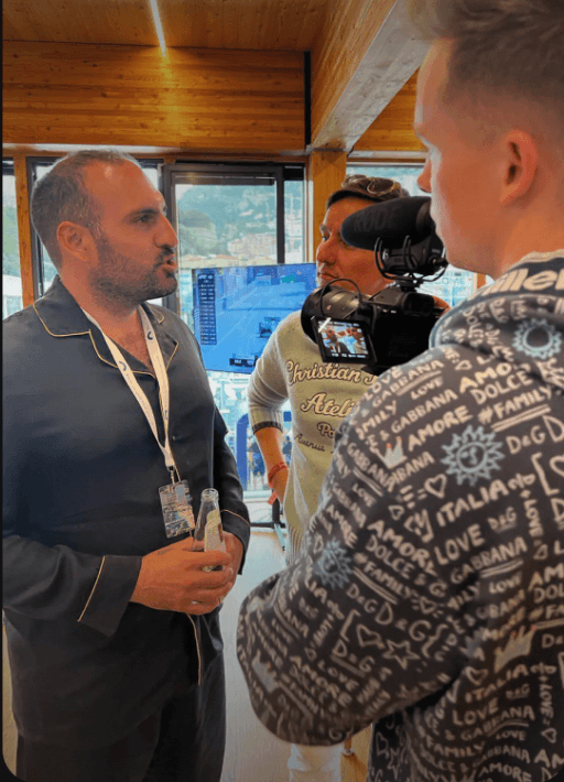 James G speaking with an interviewer beside a camera and microphone